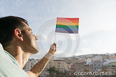 Happy Homosexual guy raised rainbow flag to the society for the freedom civil right and support the sexual liberty and identity in Stock Photo