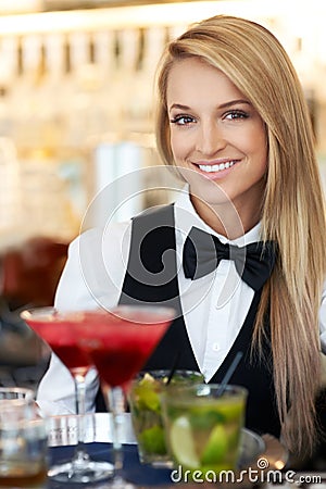 Happy hour. Portrait of a beautiful barmaid serving cocktails at a barrestaurant. Stock Photo