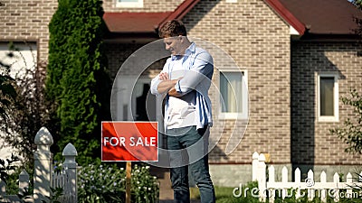 Happy house owner looking at for sale signboard against house, moving concept Stock Photo