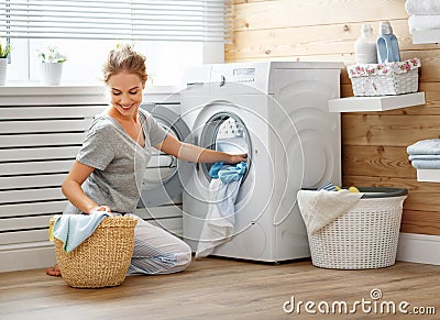 Happy housewife woman in laundry room with washing machine Stock Photo