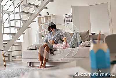 Happy indian family teen child daughter and mother bonding on sofa at home. Stock Photo