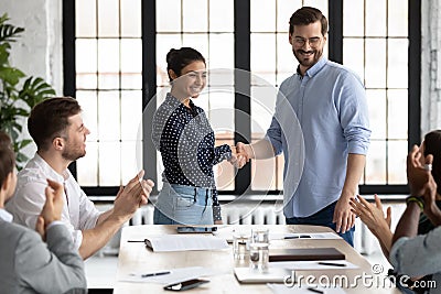 Happy Indian female team leader shaking hands with proud employee Stock Photo