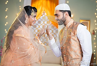 Happy indina muslim couple celebarting eid or ramadan by wishing each other at home - concept of islamic festival Stock Photo