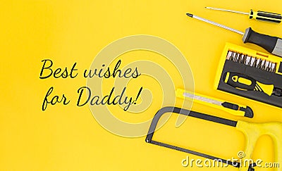 Happy inscription - Best wishes for Daddy with work tools on a yellow background. Congratulations and gifts. View from above. Stock Photo