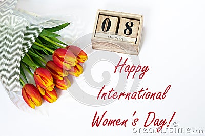 Happy International Women`s Day. Composition of bouquet of red tulip flowers and wooden cubs calendar, top view. Best greetings, Stock Photo