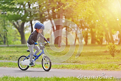 Happy kid boy of 5 years having fun in spring park with a bicycle on beautiful fall day. Active child wearing bike helmet Stock Photo