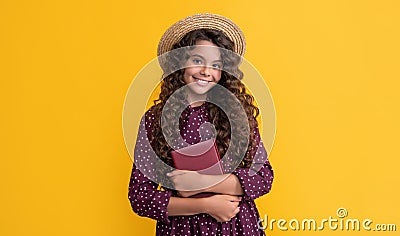 happy kid with frizz hair hold book on yellow background Stock Photo