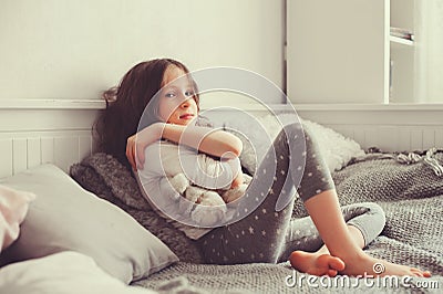 Happy kid girl playing with teddy bears in her room, sitting on bed Stock Photo