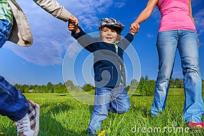 Happy kid holding parents hands in park Stock Photo