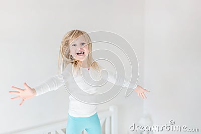 Happy kid jumping over bed. Cute little blond girl having fun indoors. Happy and careless childhood concept Stock Photo