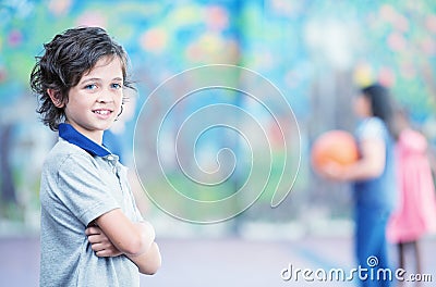 Happy kid smiling in schoolyard with other chilldren playing on Stock Photo