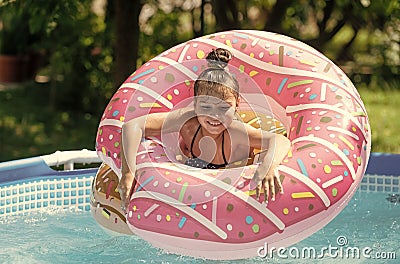 Happy kid swim in donut pool float in swimming pool on sunny summer day, floatation Stock Photo