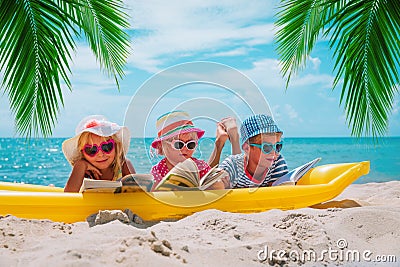 Happy kids- boy and girls read books on beach, family vacation Stock Photo