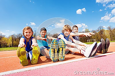 Happy kids doing stretching exercises on a stadium Stock Photo