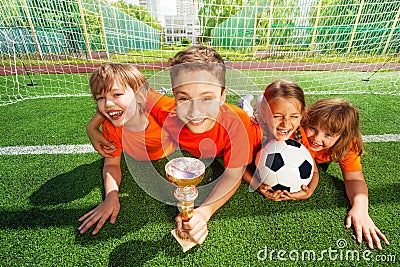 Happy kids laying on grass with golden goblet Stock Photo
