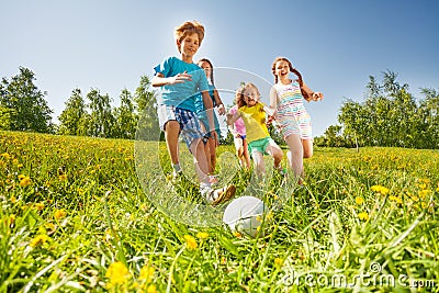 Happy kids playing football in green field Stock Photo