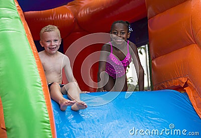 Happy kids sliding down an inflatable bounce house Stock Photo