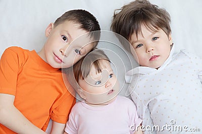 Happy kids, three children different ages lying, portrait of boy, little girl and baby girl, happiness in childhood of siblings Stock Photo