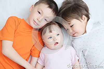 Happy kids, three laughing children different ages lying, portrait of boy, little girl and baby girl, happiness in childhood Stock Photo