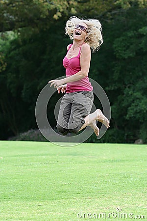 Happy lady in fifties jumping for joy Stock Photo