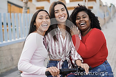 Happy latin girls having fun with electric scooter outdoor in city - Main focus on center woman face Stock Photo