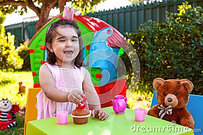 Happy laughing baby toddler girl in outdoor second birthday party holding candle Stock Photo