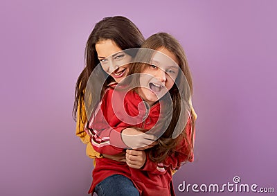 Happy laughing beautiful young mother holding and hugging her joyful daughter in fashion trendy yellow and red hoodie together on Stock Photo