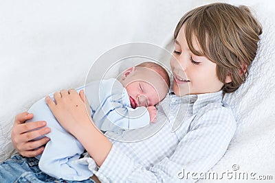 Happy laughing boy holding his sleeping newborn baby brother Stock Photo