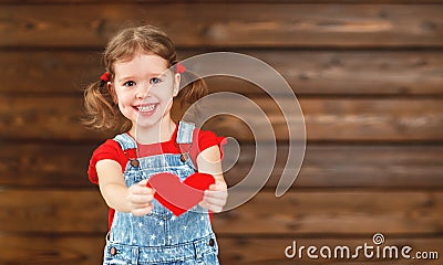 Happy laughing child girl with heart Valentine`s Day, wooden Stock Photo