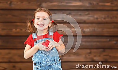 Happy laughing child girl with heart Valentine`s Day, wooden Stock Photo