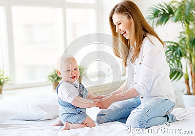 Happy laughing mother and baby playing in bed Stock Photo