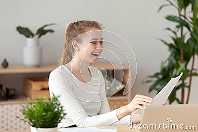 Happy laughing woman sitting at the desk reading documents Stock Photo