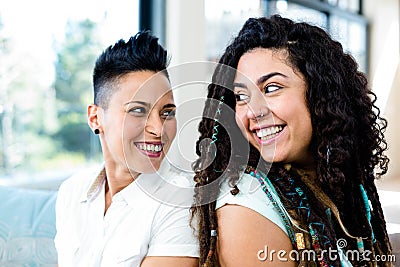 Happy lesbian couple sitting back to back Stock Photo