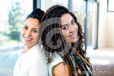 Happy lesbian couple sitting back to back Stock Photo