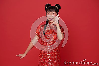 Happy Little asian child wearing traditional cheongsam qipao dress shout announcement Happy Chinese new year 2024 isolated on red Stock Photo