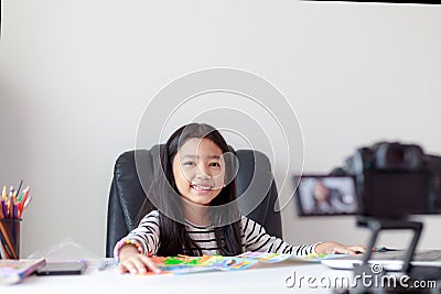 Happy little Asian girl sitting at the white table and live streaming for social media with happiness by camera select focus Stock Photo
