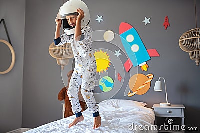 Happy little boy with astronaut helmet jumping on bed Stock Photo