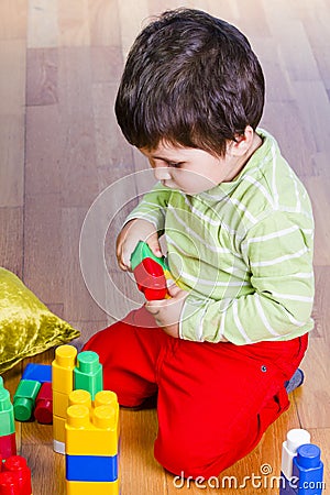 A happy little boy is building a colorful toy Stock Photo