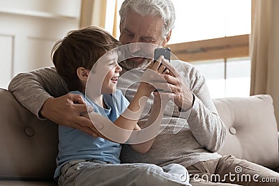 Happy senior grandfather and little grandson use smartphone Stock Photo