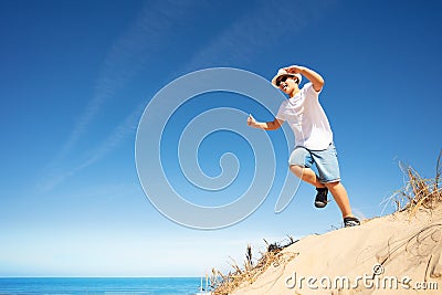 Cute boy in white jump from sand dune on a beach Stock Photo