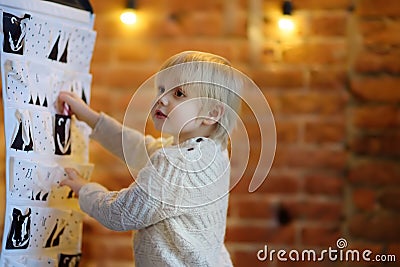 Happy little boy takes sweet from advent calendar on Christmas eve Stock Photo