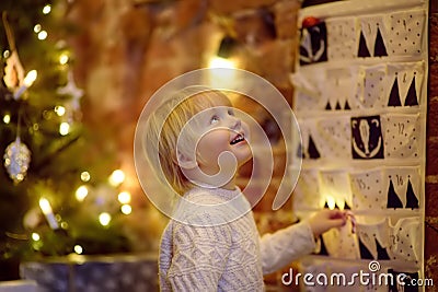 Happy little boy takes sweet from advent calendar on Christmas eve Stock Photo