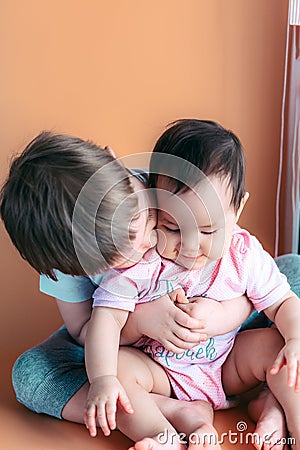 Happy little brother playing hugs his sister baby, boy and girl embraces kisses, concept love and parenting Stock Photo