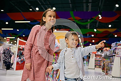 Happy little children walk among display cases with toys in store Stock Photo