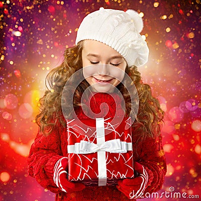 Happy little girl with Christmas gift over lights background Stock Photo