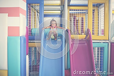 Happy little girl descends from the toboggan. Stock Photo