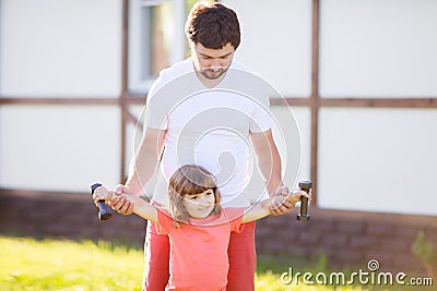 Happy little girl and her father lifting dumbbells outdoors Stock Photo