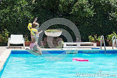 Happy little girl jumps in the pool; summertime background Stock Photo