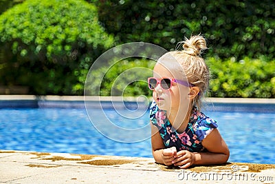 Happy little girl in outdoor swimming pool on hot summer day. Kids learn to swim. Children play in tropical resort. Family beach Stock Photo