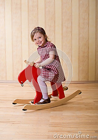 Happy little girl play with toy wooden deer Stock Photo